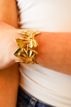 Gold bow cuff bracelet featuring an elegant linked bow design, perfect for adding a statement touch to any outfit.