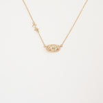 Love Elise reversible necklace featuring a pearl-inspired pendant framed in gold with a delicate chain and bow detail."