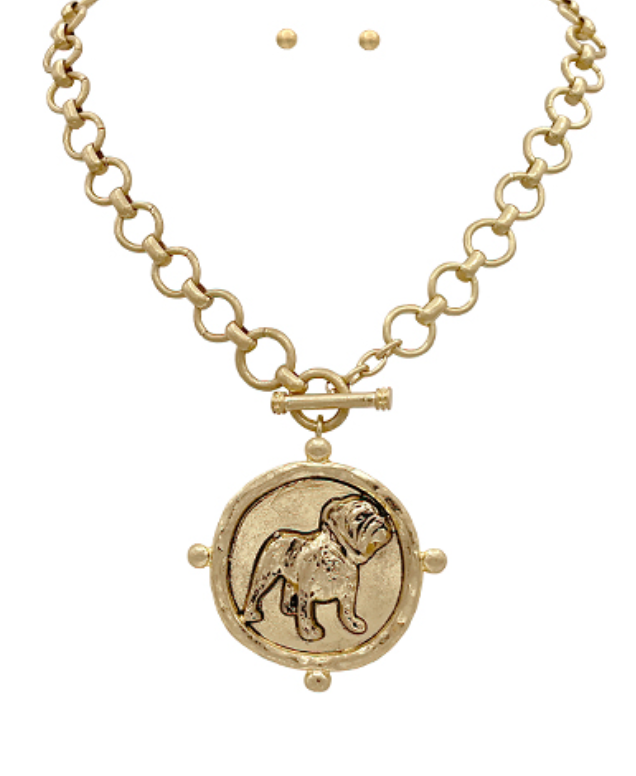 A bold gold-toned medallion necklace featuring an intricately detailed bulldog pendant on a chunky chain with a toggle clasp.
