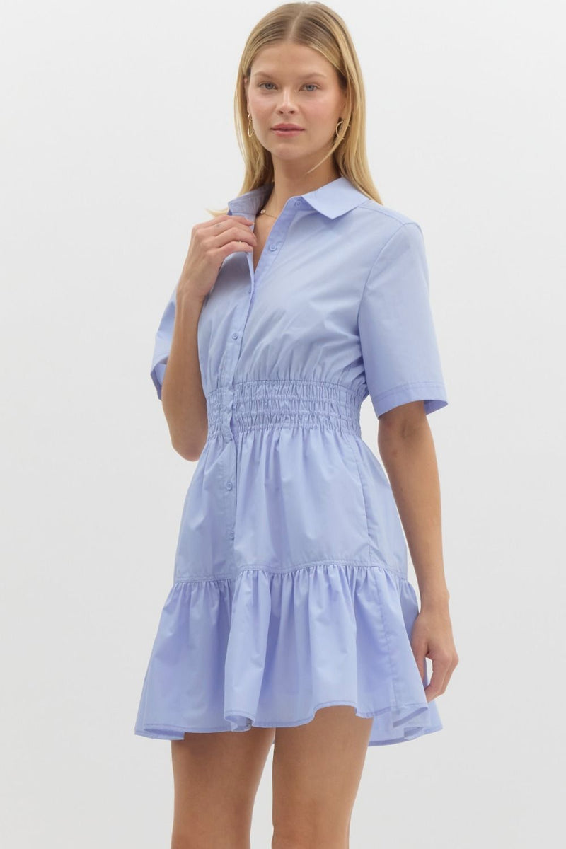 light blue short-sleeve shirt dress with a collared neckline, button-down front, and smocked waist. The dress has a tiered skirt and a relaxed yet flattering fit.