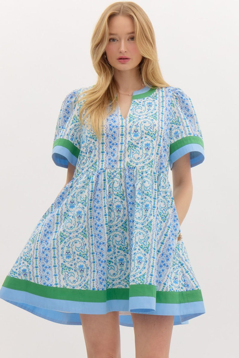  blue and green paisley-print cotton dress with contrast trim, a V-neckline, and structured short sleeves, evoking a fresh and breezy summer aesthetic.