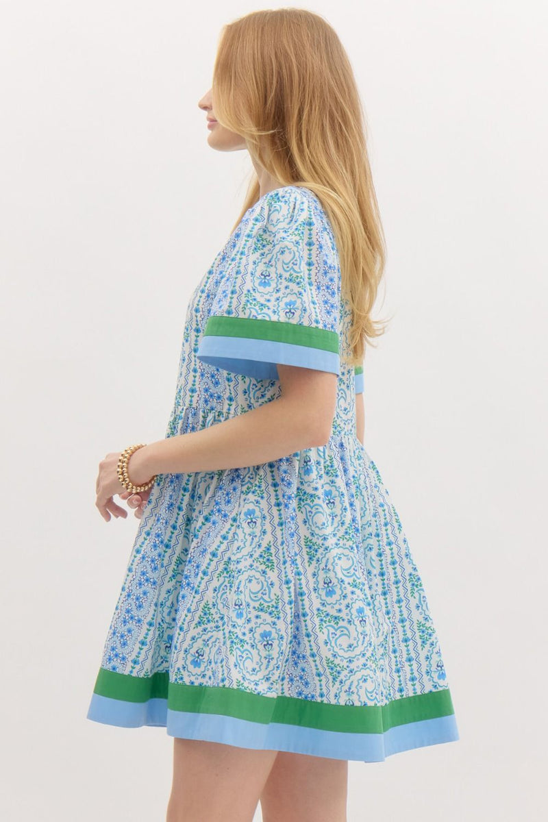  blue and green paisley-print cotton dress with contrast trim, a V-neckline, and structured short sleeves, evoking a fresh and breezy summer aesthetic.