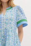  blue and green paisley-print cotton dress with contrast trim, a V-neckline, and structured short sleeves, evoking a fresh and breezy summer aesthetic.