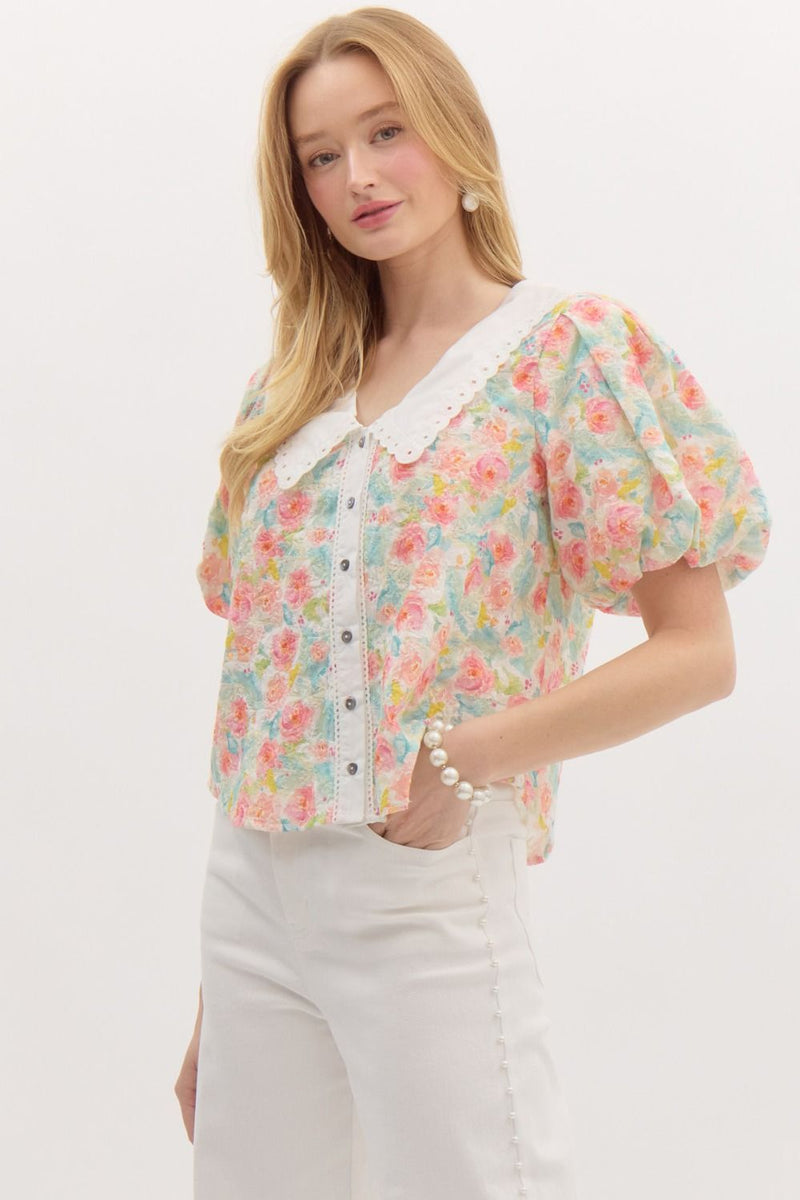 pastel floral puff-sleeve blouse with a delicate eyelet lace collar and button-down front. The top features a soft, textured fabric with a romantic vintage-inspired design.