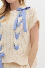 Cream knit sweater with blue ribbon details and cable knit pattern