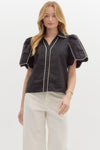 Milan Piped Blouse, a sophisticated black button-down top with statement puff sleeves and contrasting white piping along the collar, front, and sleeves. The structured yet flowy silhouette adds a modern touch to a classic design.